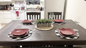Una mesa de comedor dispuesta con platos rojos, vasos y un centro de mesa con la palabra "HOME".