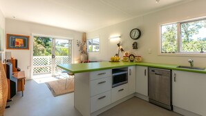 Una cocina moderna con armarios blancos, encimera verde y electrodomésticos de acero inoxidable.