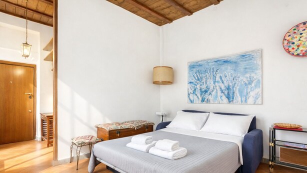 Un dormitorio con cama, una mesita de noche, una lámpara, un cuadro y una puerta de madera.