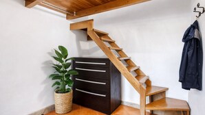 Una escalera de madera con un armario oscuro y una planta en maceta a un lado.