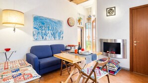 Una sala de estar con sofá, una mesa, chimenea y un cuadro en la pared.
