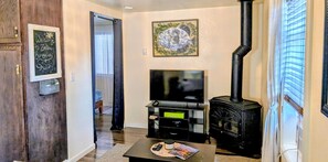 Ein Wohnzimmer mit Fernseher, einem schwarzen Kaminofen und einem begrüßungsschild im Bilderrahmen.