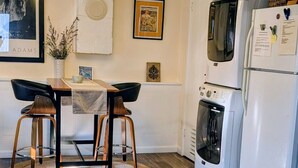 Une cuisine équipée d’une table à manger, de chaises, d’un lustre, d’un réfrigérateur et d’un lave-linge.