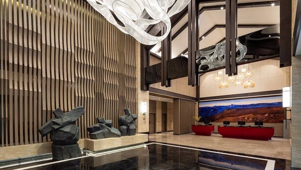 A modern lobby with a reflective floor, a reception desk, and a large abstract painting on the wall. - Ramada by Wyndham Daocheng (Garze)