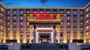 A multi-story hotel with a prominent entrance, large windows, and a well-lit facade. - Ramada by Wyndham Daocheng (Garze)