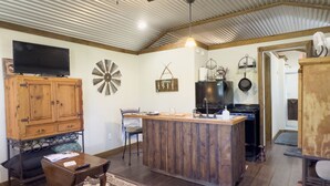 Een keuken met een houten kookeiland, een aan de muur bevestigde televisie en een plafondventilator.
