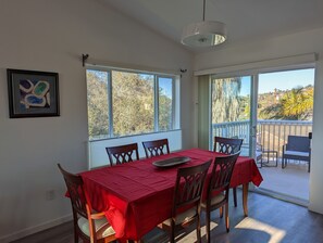 A dining area with a red tablecloth, six wooden chairs, and a pendant light.