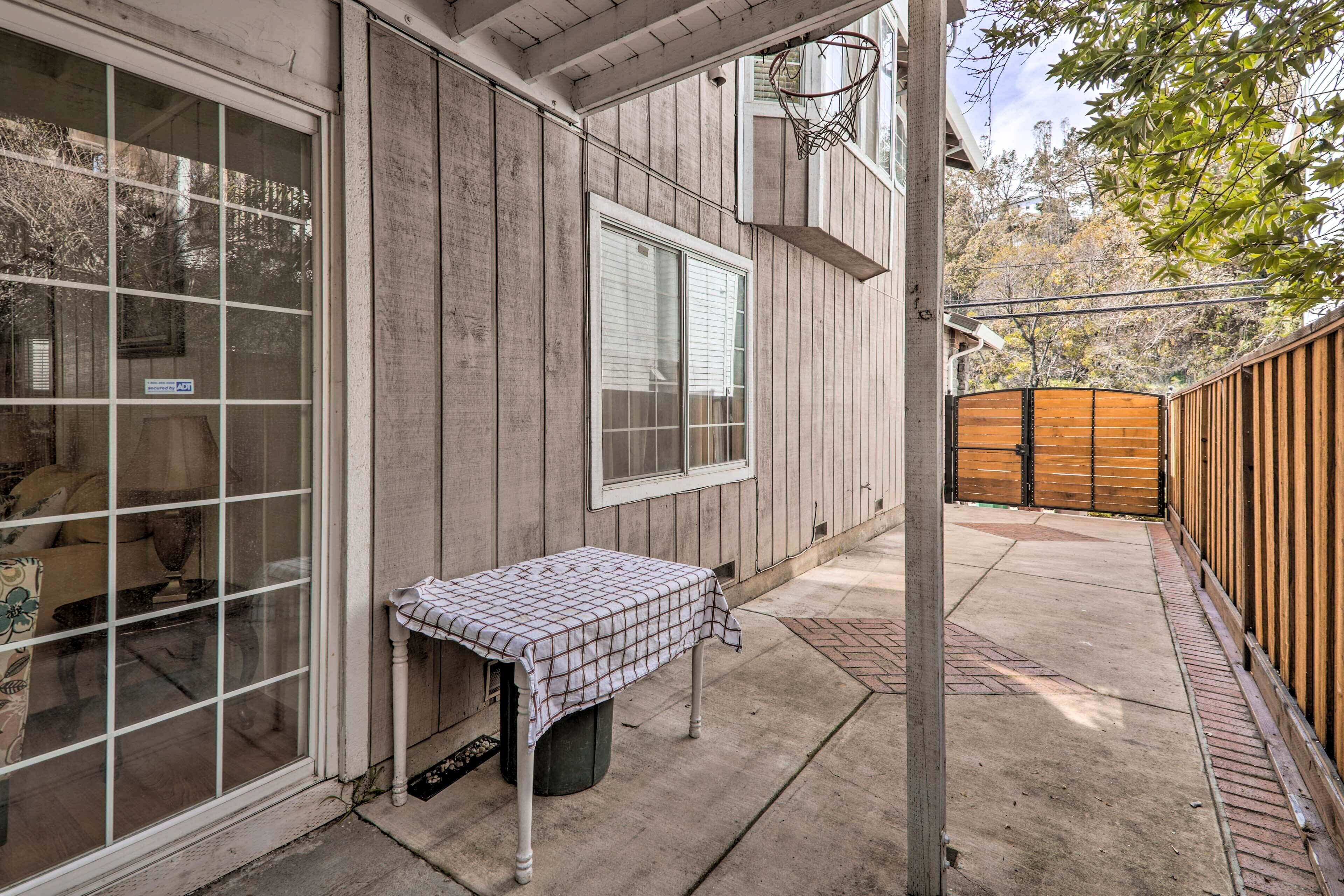 Un patio con mesa y sillas, una canasta de baloncesto y una valla de madera.