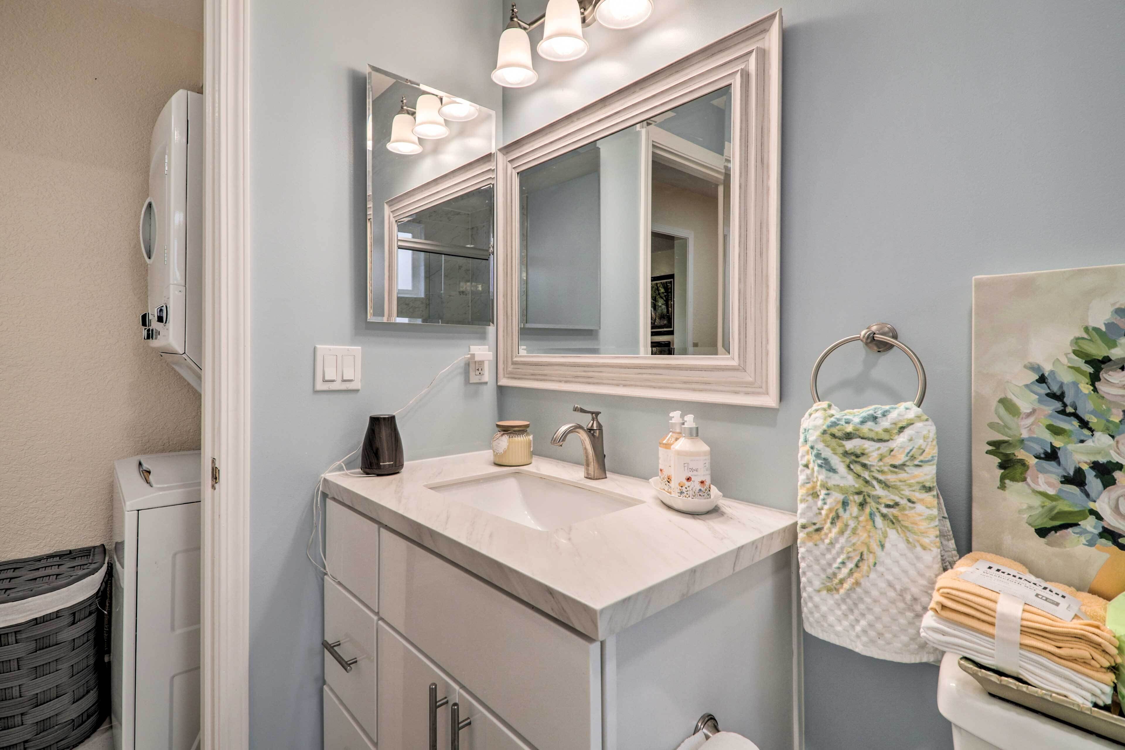 Une salle de bain avec un meuble-lavabo blanc, deux miroirs, un lavabo et un porte-serviettes.