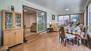 Un espace repas comprenant une table en bois, des chaises et une vue sur l’extérieur grâce à de grandes fenêtres.