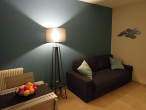 A living room with a floor lamp, a sofa, a table with a fruit bowl, and a wall with decorative plates. - CANNES BORD DE MER FACE PLAGE (Cannes)