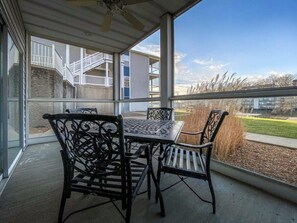 Eine überdachte Terrasse mit Tisch und Stühlen mit Blick auf eine Rasenfläche und Gebäude.