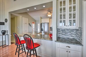 A kitchen with a central island, two bar stools, and a refrigerator.