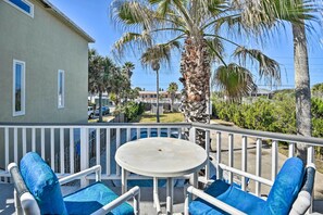 Enjoy a peaceful retreat on the balcony with a round table and two cushioned chairs, offering a serene view of the surrounding residential area with palm trees.