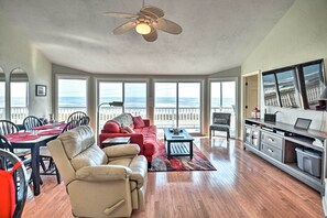 Relax in a spacious living area with expansive ocean views through large windows, featuring a leather sofa, a couch, and a comfortable armchair.