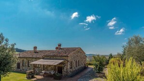 Un edificio in pietra con tetto in tegole, un portico coperto e un muro di pietra.