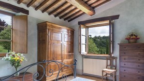 Una stanza con un ampio armadio in legno, una finestra vista verde, un termosifone e una sedia.