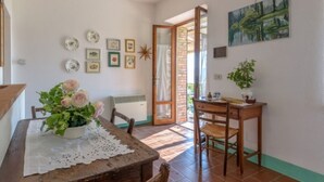 Un comedor con una mesa de madera, sillas y un florero. Hay cuadros en la pared y un cuadro sobre la mesa.