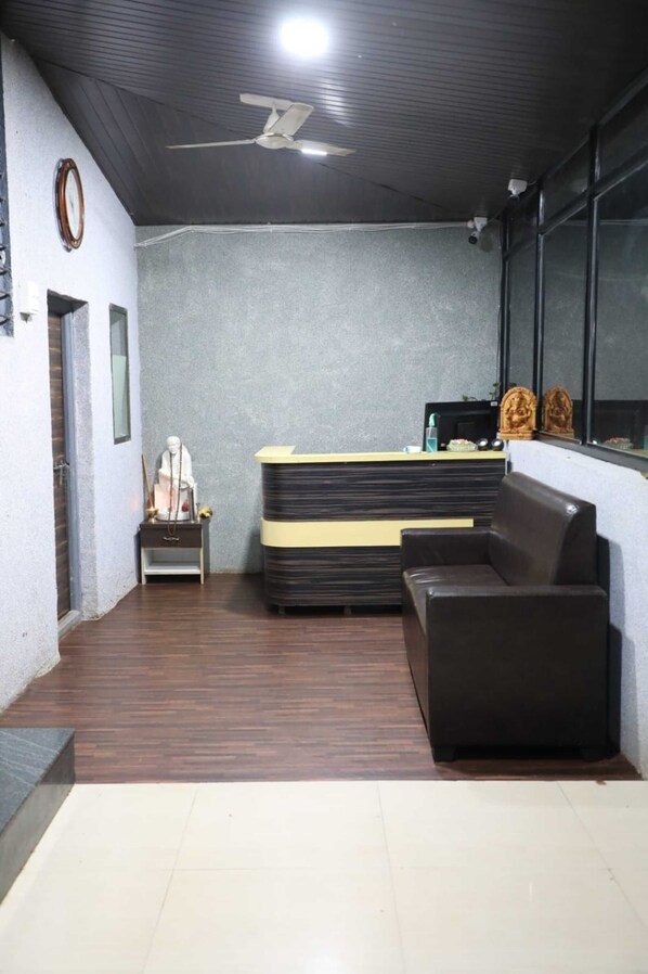 A reception area with a desk, seating, a statue, and a ceiling fan.
