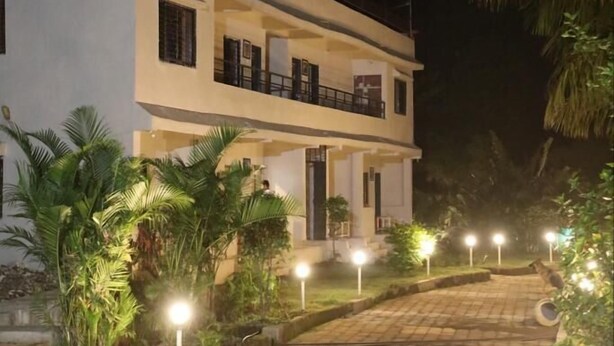 A two-story building with a balcony on the upper floor, surrounded by palm trees and a paved pathway. - Wanderlust Resort (Akola)