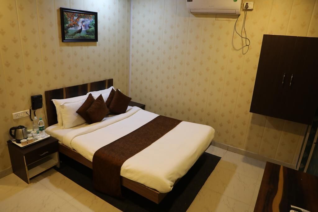 Une chambre d’hôtel équipée d’un lit, d’une table de chevet, d’une armoire et d’un climatiseur fixé au mur.