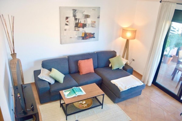 A living room with a dark blue sofa, a coffee table, a lamp, and a painting on the wall.