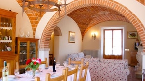 A dining area with a brick archway, wooden furniture, and a table set for a meal.