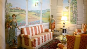 A room with a sofa, chairs, a lamp, and a mural of a landscape. - Villa Del Portico. AC, Private pool. Pets allowed (Castiglion Fiorentino)