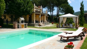 A swimming pool with lounge chairs, a gazebo, and a building with a balcony. - Villa Del Portico. AC, Private pool. Pets allowed (Castiglion Fiorentino)