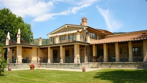 A large, two-story building with a stone facade, multiple balconies, and a spacious courtyard. - Villa Del Portico. AC, Private pool. Pets allowed (Castiglion Fiorentino)