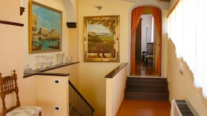 A staircase with a wooden handrail and a chair with a floral cushion. - Villa Del Portico. AC, Private pool. Pets allowed (Castiglion Fiorentino)