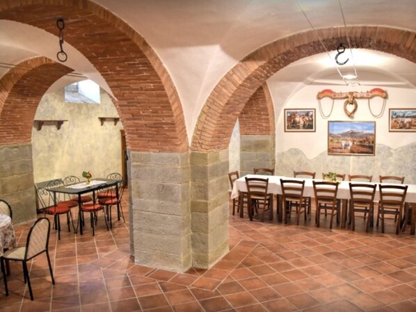 A dining area with brick arches, a long table, and chairs.