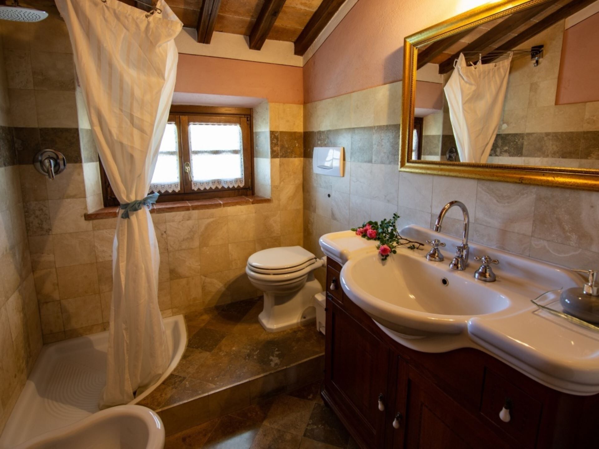 Baño con ducha, inodoro y tocador con lavabo.