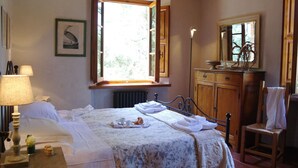 Une chambre à coucher comprenant un lit, une table de chevet, une lampe, une fenêtre, une commode, un miroir et une chaise.