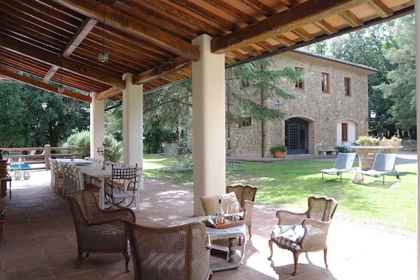 An outdoor patio with wicker furniture, a stone building in the background, and a well-maintained lawn.