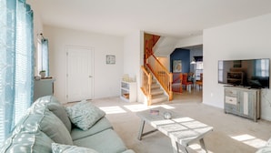 A living room with a sofa, coffee table, and a television. There is a staircase leading to another room. - < 3 Mi to Bethany Beach: Family Gem w/ Game Room (Millville)
