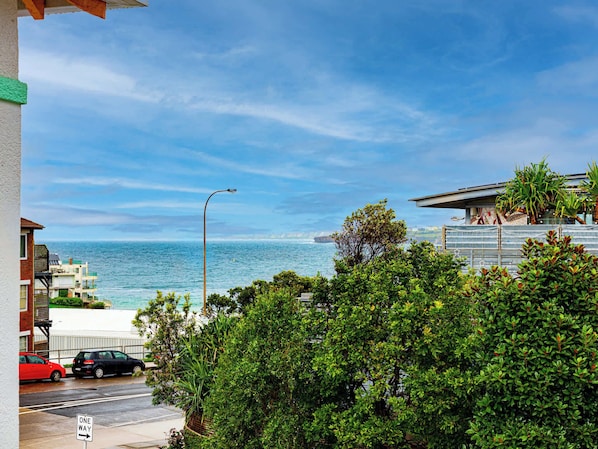 A coastal street with a view of the ocean, a 'ONE WAY' sign, and a street lamp.