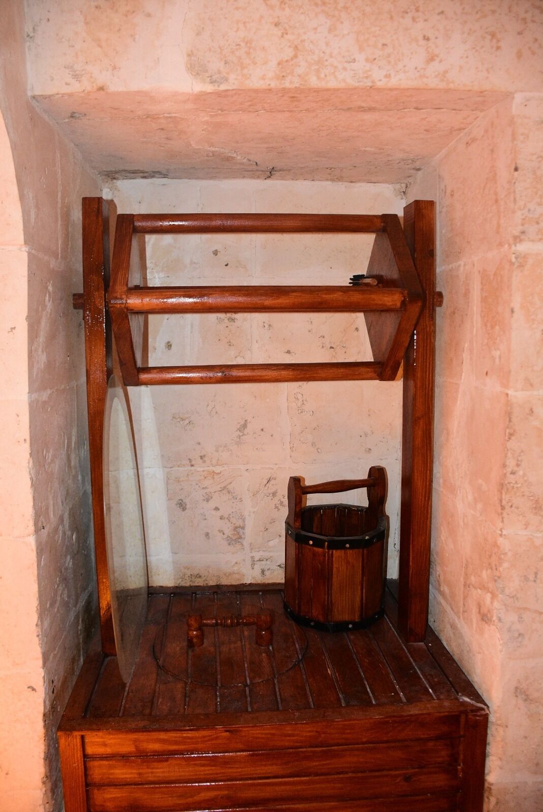 A wooden shelf unit with a wooden bucket.