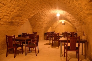 Un espacio comedor subterráneo con paredes de piedra y mesas y sillas de madera.