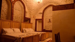 Quarto com duas camas de madeira, uma cadeira de madeira e uma parede de pedra.