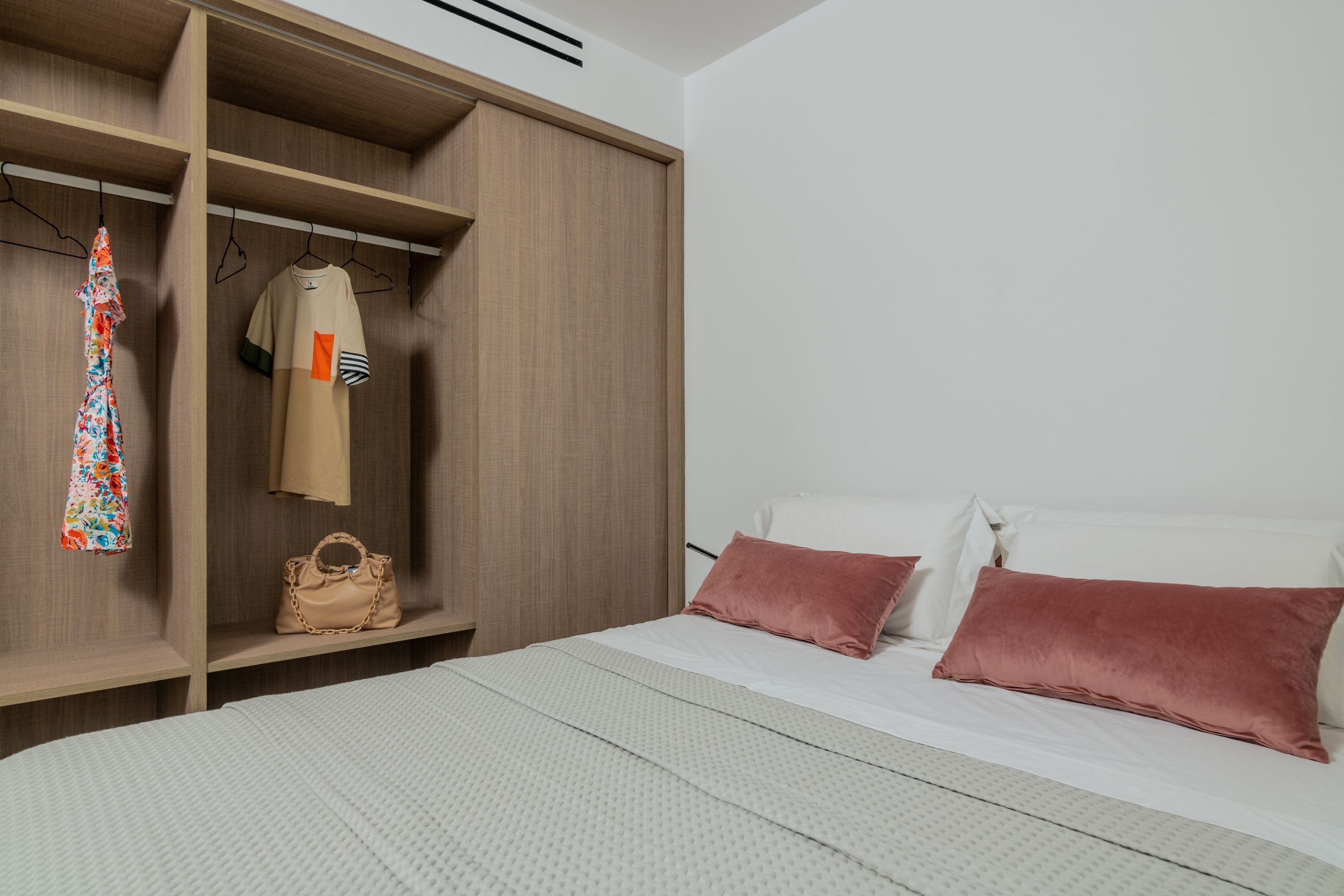 A bedroom with a bed, a wardrobe, and a hanging garment rack.
