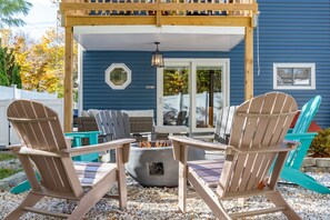 Ein überdachter Patio-Bereich mit Adirondack-Stühlen, einer Feuerstelle und einer Pergola.
