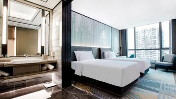 A modern hotel room with a large bed, a bathroom with a mirror and sink, and a view of the city.
