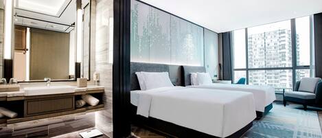 A modern hotel room with a large bed, a bathroom with a mirror and sink, and a view of the city.