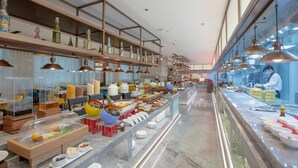 A buffet area with various food items, a kitchen area with a chef, and a seating area with tables and chairs. - Holiday Inn Taiyuan City Center (Taiyuan)