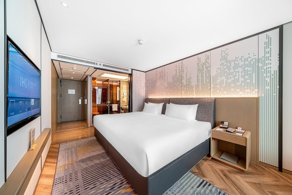 A modern hotel room with a large bed, a bedside table, a TV, and a wall-mounted artwork. - Holiday Inn Taiyuan City Center (Taiyuan)