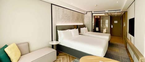 A hotel room with a large bed, a sofa, a small table, and a TV.