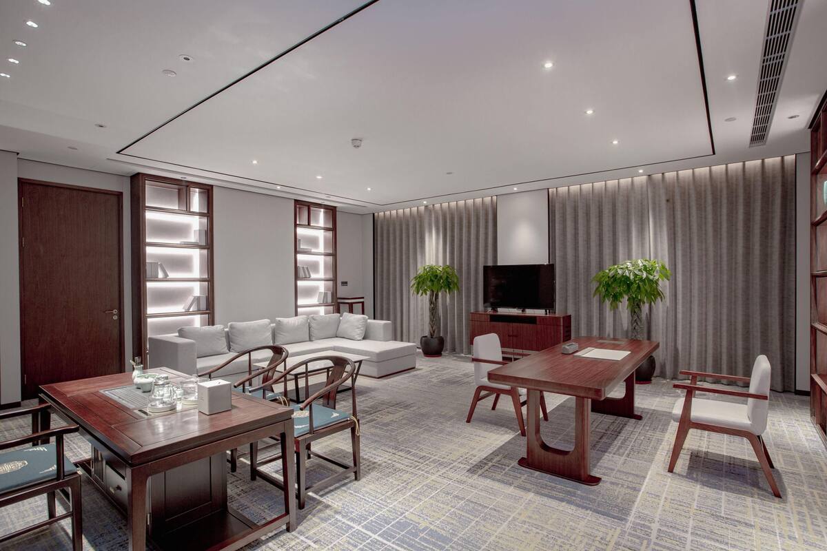 A modern living room with a sofa, a TV, a dining table, and chairs.