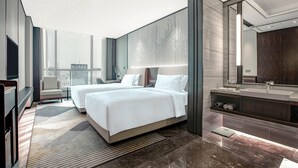 A modern hotel room with two beds, a large window, a bathroom with a mirror and sink, and a city view. - Holiday Inn Taiyuan City Center (Taiyuan)