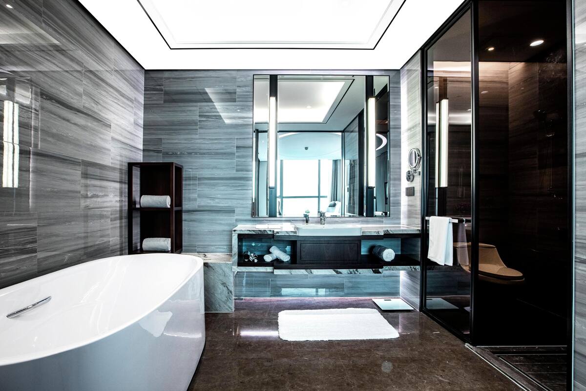 A modern bathroom with a freestanding bathtub, a glass-enclosed shower, and a large mirror.